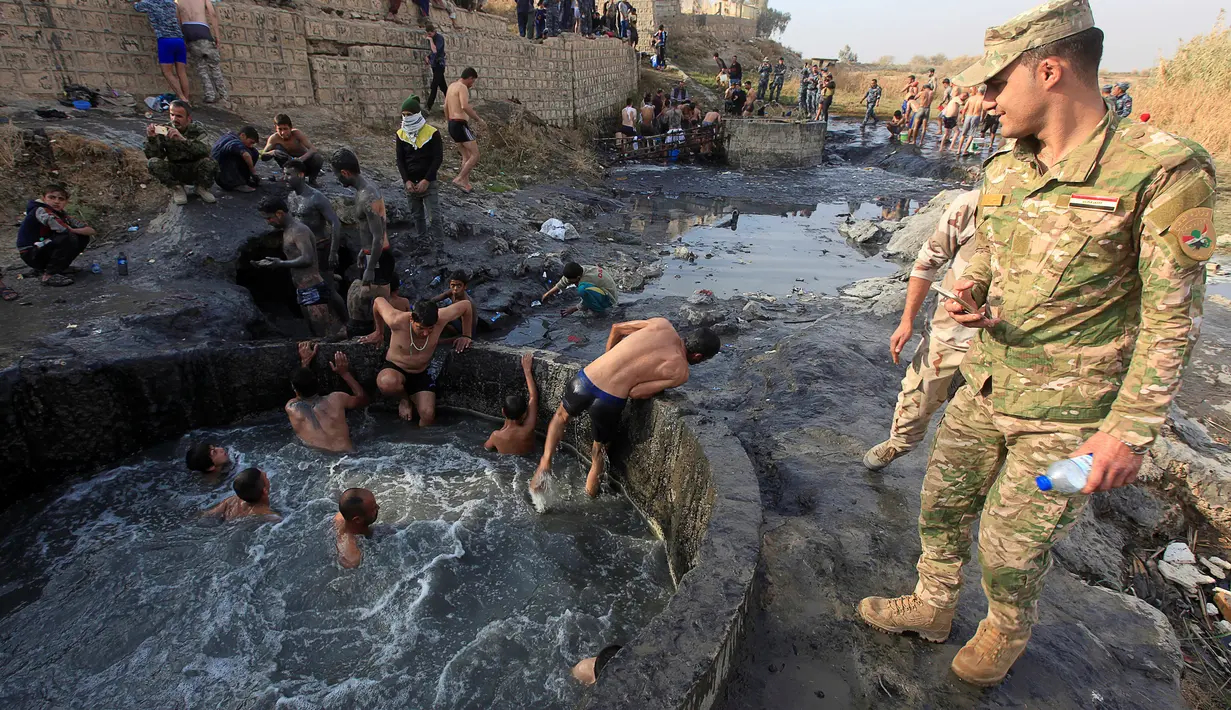 Para tentara Irak saat berada di kolam belerang di Hammam al-Ali, Mosul, Irak, (9/11). Di tengah perang melawan ISIS, mereka melepaskan penat dan lelah dengan berenang di Kolam belerang. (REUTERS/Alaa Al-Marjani)