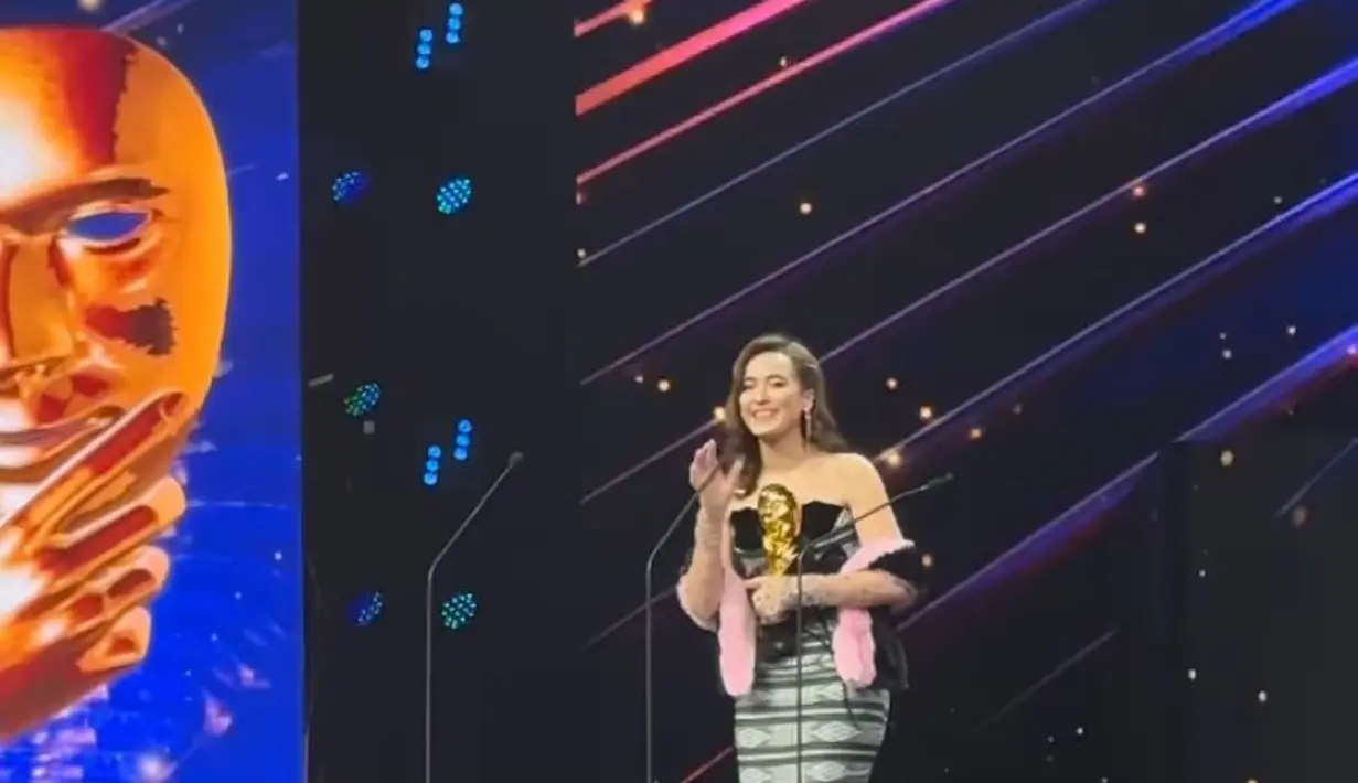 Bawa pulang piala, Mawar Eva mengenakan tube dress motif tenun dengan aksen hitam pada bagian dada dan membawa selendang bulu pink. Credit: [@untungadaaji]