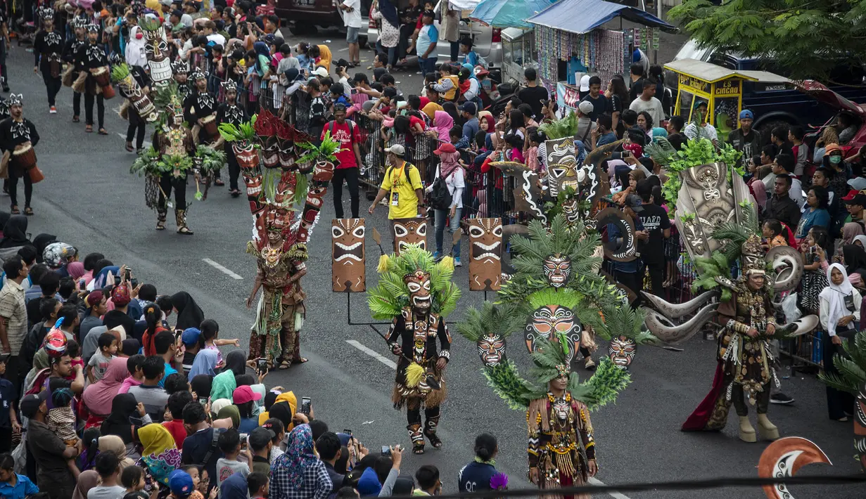 Warga menyaksikan peserta menampilkan kreasi kostum dalam Jember Fashion Carnaval (JFC) di Jember, Provinsi Jawa Timur pada Minggu (4/8/2019). Kegiatan ini mengangkat tema 'tribal grandeur', dengan menghadirkan keagungan 8 suku di dunia. (Photo by JUNI KRISWANTO / AFP)