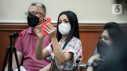 Aktris Nirina Zubir (tengah) mengambil gambar saat menghadiri sidang lanjutan kasus mafia tanah di Pengadilan Negeri Jakarta Barat, Jakarta, Selasa (7/6/2022). Nirina Zubir melaporkan mantan ART almarhumah ibunya, yang bernama Riri Khasmita pada November 2021. (Liputan6.com/Faizal Fanani)