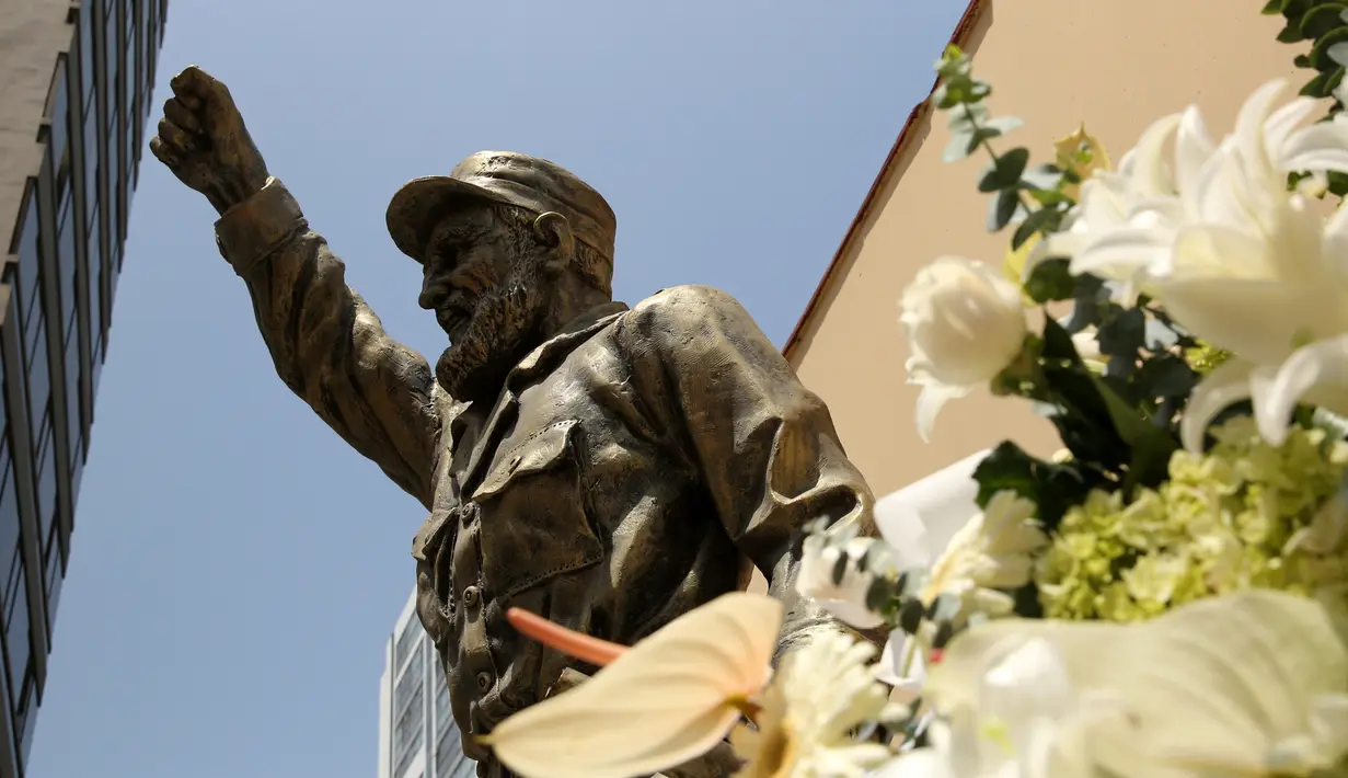 Karangan bunga terlihat di sebelah patung Fidel Castro setelah pengumuman kematiannya di Kedubes Kuba di Lima, Peru, Senin (28/11). Pemimpin revolusioner Kuba Fidel Castro meninggal dunia pada usia 90 tahun pada 25 November kemarin. (REUTERS/Mariana Bazo)