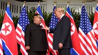 Presiden AS, Donald Trump bertemu dengan Pemimpin Korea Utara, Kim Jong-un di resor Capella, Pulau Sentosa, Singapura, Selasa (12/6). Pertemuan ini merupakan yang pertama kalinya bagi pemimpin AS dan Korut untuk bertatap muka. (SAUL LOEB/AFP)