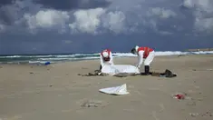 Kelompok Bulan Sabit Merah Libya memasukkan jenazah yang diduga imigran yang tewas tenggelam, ke kantong mayat di pantai Khoms, sebelah timur Tripoli, Minggu (25/10). Sedikitnya 40 jasad telah ditemukan di pantai Libya. (REUTERS/Ismail Zitouny)