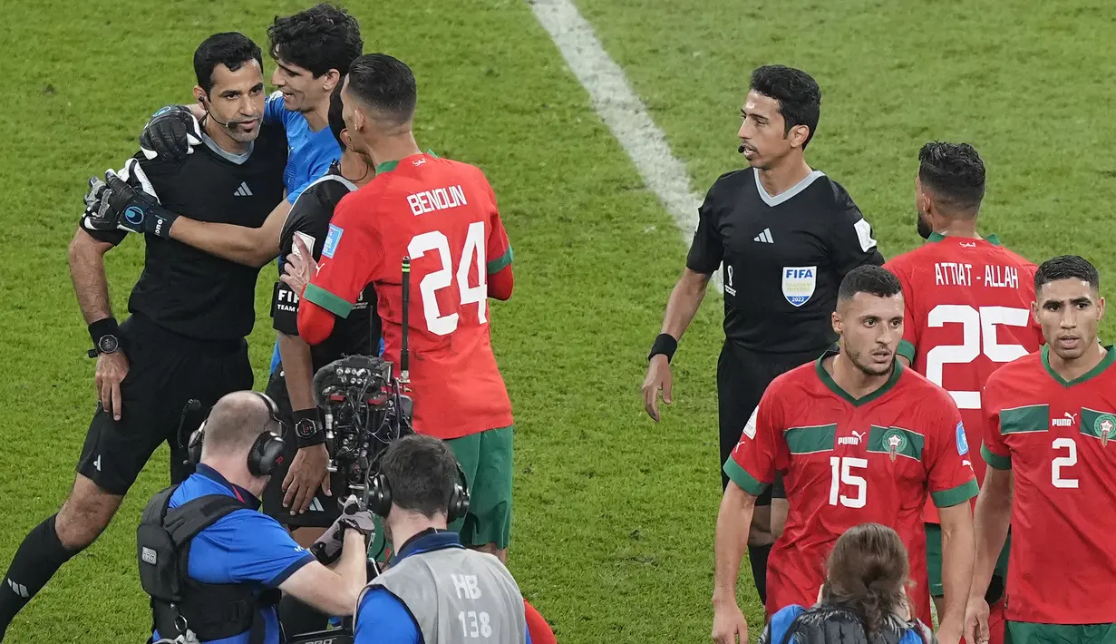 Ditengah derasnya serbuan pemain Maroko terhadap wasit, sosok penjaga gawang Maroko, Yassine Bounou lah yang menjadi penengah. Ia menghampiri wasit Abdulrahman Al Jassim yang terlihat akan mengeluarkan kartu dari kantongnya untuk menghukum pemain Maroko yang melakukan protes setelah laga usai. (AP Photo/Martin Meissner)