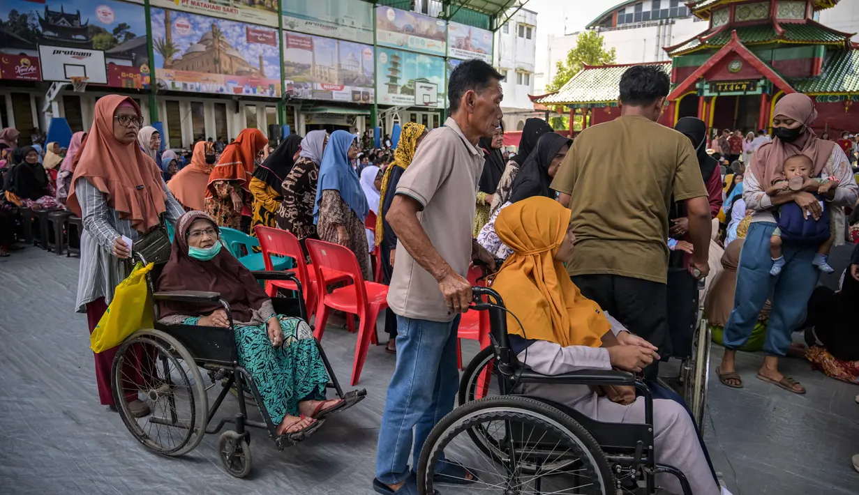 Berbekal undangan resmi, warga datang secara bergelombang untuk mencairkan bantuan uang tunai dan paket sembako. Tampak dalam foto, warga mengantre untuk menerima bantuan uang tunai di masjid Cheng Hoo, Surabaya, Jawa Timur pada Rabu 4 Maret 2026. (JUNI KRISWANTO/AFP)