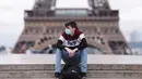 Seorang pria yang mengenakan masker beristirahat di Istana Trocadero tak jauh dari Menara Eiffel di Paris, 10 Juli 2020. Jumlah kematian terkait corona di Prancis naik menjadi 30.004, sementara jumlah pasien yang dirawat di rumah sakit atau di ICU terus turun pada Jumat (10/7). (Xinhua/Gao Jing)