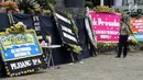 Petugas kepolisian mengamati karangan bunga ucapan belasungkawa atas kematian KPK di Gedung Merah Putih, Jakarta, Senin (9/9/2019). Keberadaan kain hitam dan karangan bunga ini merupakan bentuk protes atas revisi Undang-undang KPK yang dinilai dapat melemahkan KPK. (merdeka.com/Dwi Narwoko)