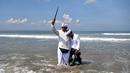 Seorang pria memegang keris saat sembahyang upacara Melasti di pantai Petitenget dekat Denpasar, di pulau resor Bali, Indonesia pada 19 Maret 2023. (AFP/SONNY TUMBELAKA)