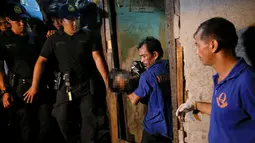 Petugas membawa tubuh korban yang tewas ditembak oleh orang tak dikenal dari dalam rumah di Manila, Filipina (1/11). Lima orang tersebut tewas di dalam rumah yang dikenal sebagai sarang obat-obatan terlarang. (REUTERS/Damir Sagolj