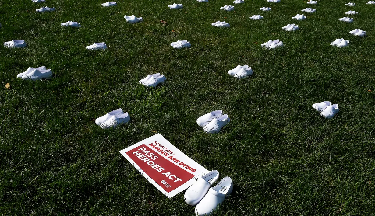Serikat perawat Amerika Serikat (AS) meletakkan 164 pasang sepatu putih di luar US Capitol di Washington, DC pada Selasa (21/7/2020). Sepatu-sepatu itu melambangkan para perawat yang tewas akibat covid-19 dan menuntut Senat bertindak cepat melindungi perawat di garis depan. (Olivier DOULIERY/AFP)