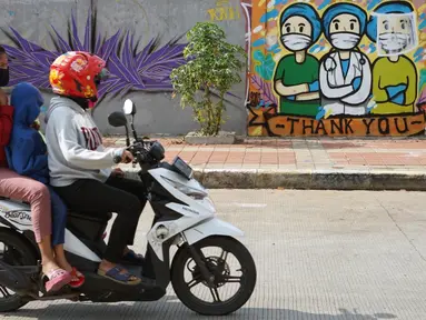 Pengendara sepeda motor melintas di depan mural bertema pandemi virus corona COVID-19 di kawasan Sunter, Jakarta, Selasa (2/6/2020). Mural tersebut dibuat sebagai wujud dukungan terhadap tenaga medis serta masyarakat agar tetap semangat menghadapi pandemi COVID-19. (Liputan6.com/Immanuel Antonius)