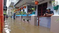 Warga bermain ponsel saat banjir merendam RW 06 kawasan Mekarsari, Depok, Jawa Barat, Sabtu (20/2/2021). Banjir yang disebabkan meluapnya aliran Kali Cipinang Timur ini terjadi akibat intensitas hujan tinggi di wilayah tersebut (Liputan6.com/Herman Zakharia)