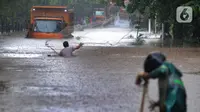 Warga menjala ikan di tengah jalan yang tertutup banjir di kawasan TB Simatupang, Jakarta Selatan, Sabtu (20/2/2021). Banjir terjadi akibat luapan Kali Serua yang berada di pinggir jalan tol. (merdeka.com/Arie Basuki)