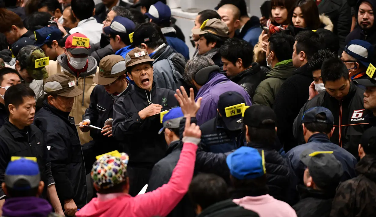 Pedagang grosir berpartisipasi dalam tradisi lelang Tahun Baru di Pasar ikan Toyosu, Tokyo, Minggu (5/1/2020). Lelang terbesar ini digelar pertama usai Tahun Baru, di mana pembeli dari toko grosir hingga taipan sushi akan datang untuk mencari ikan terbaik. (Kazuhiro NOGI / AFP)