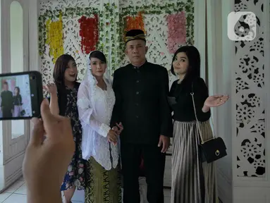 Pasangan Ririn  dan Zaenal berfoto bersama kerabat usai melangsungkan pernikahan di KUA Kecamatan Matraman, Jakarta, Selasa (22/02/2022). Sejumlah pasangan sengaja melangsungkan pernikahan pada hari ini yang memiliki tanggal, bulan, dan tahun unik yakni 22-02-2022. (Liputan6.com/Herman Zakharia)
