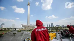 Petugas Pemadam Kebakaran menyemprotkan cairan disinfektan di lingkungan Monas, Jakarta, Rabu (17/6/2020). Penyemprotan dilakukan untuk mencegah penyebaran COVID-19 dalam rangka persiapan pembukaan kembali Monumen Nasional (Monas) pada Sabtu, 20 Juni 2020.  (Liputan6.com/Faizal Fanani)