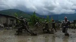 Para petani berlumur lumpur saat bermain pada Hari Padi Nasional di sawah Desa Tokha, Kathmandu, Nepal, Senin (29/6/2020). Para petani di Nepal merayakan Hari Padi Nasional sebagai musim tanam padi tahunan dimulai. (PRAKASH MATHEMA/AFP)