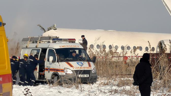 Polisi berjaga saat petugas penyelamat mengevakuasi korban jatuhnya pesawat maskapai Bek Air di dekat Bandara Almaty, Kazakhstan, Jumat (27/12/2019). Pesawat Bek Air sedang dalam perjalanan dari Bandara Internasional Almaty menuju Nur-Sultan saat pesawat hilang kontak. (AP Photo/Vladimir Tretyakov)