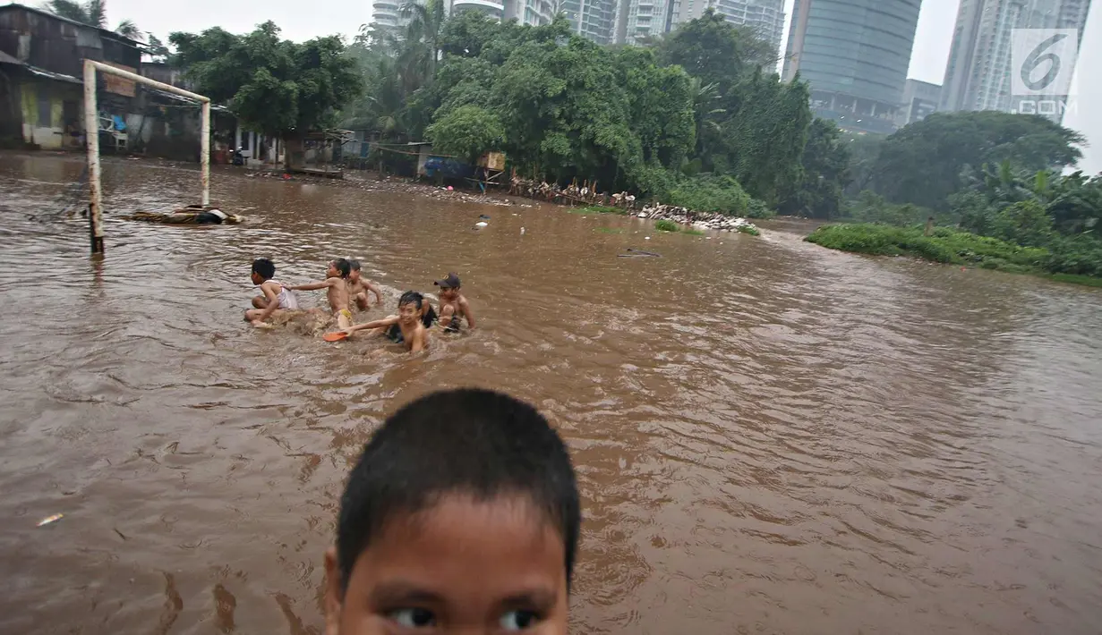 Anak-anak bermain di lapangan sepak bola di kawasan Kemang, Jakarta, Kamis (16/11). Tingginya intensitas hujan dan pesatnya pembangunan menyebabkan kawasan tersebut langganan banjir yang berasal dari luapan Kali Krukut. (Liputan6.com/Immanuel Antonius)