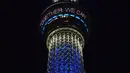 Menara Tokyo Skytree terlihat menyala dengan warna biru bertuliskan "Bersama Kita Semua Bisa Menang" di Tokyo, 5 April 2020. Ungkapan dukungan dan pesan harapan tersebut muncul di tengah merebaknya pandemi virus corona Covid-19. (CHARLY TRIBALLEAU/AFP)