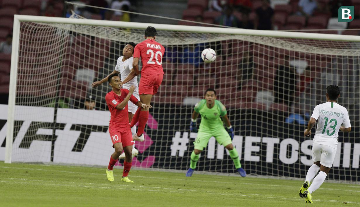 Bek Timnas Indonesia, RIcky Fajrin, duel udara dengan gelandang Singapura, Ikhsan, pada laga Piala AFF di Stadion Nasional, Singapura, Jumat (9/11). Singapura menang 1-0 atas Indonesia. (Bola.com/M. Iqbal Ichsan)