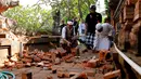 Pemuka agama memantau kerusakan pada bagian candi yang runtuh akibat gempa di Pura Lokanatha, Denpasar, Bali, Selasa (16/7/2019). Gempa Magnitudo 5,8  yang mengguncang Bali tidak menimbulkan korban jiwa, tapi sejumlah bangunan di beberapa kawasan mengalami kerusakan. (AP/Firdia Lisnawati)