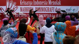 Instruktur mengajak peserta senam pagi saat aksi Keluarga Indonesia Menolak Narkoba, Pornografi, dan Kekerasan Terhadap Perempuan dan Anak saat Car Free Day di Bundaran HI, Jakarta, Minggu (4/9). (Liputan6.com/Johan Tallo)