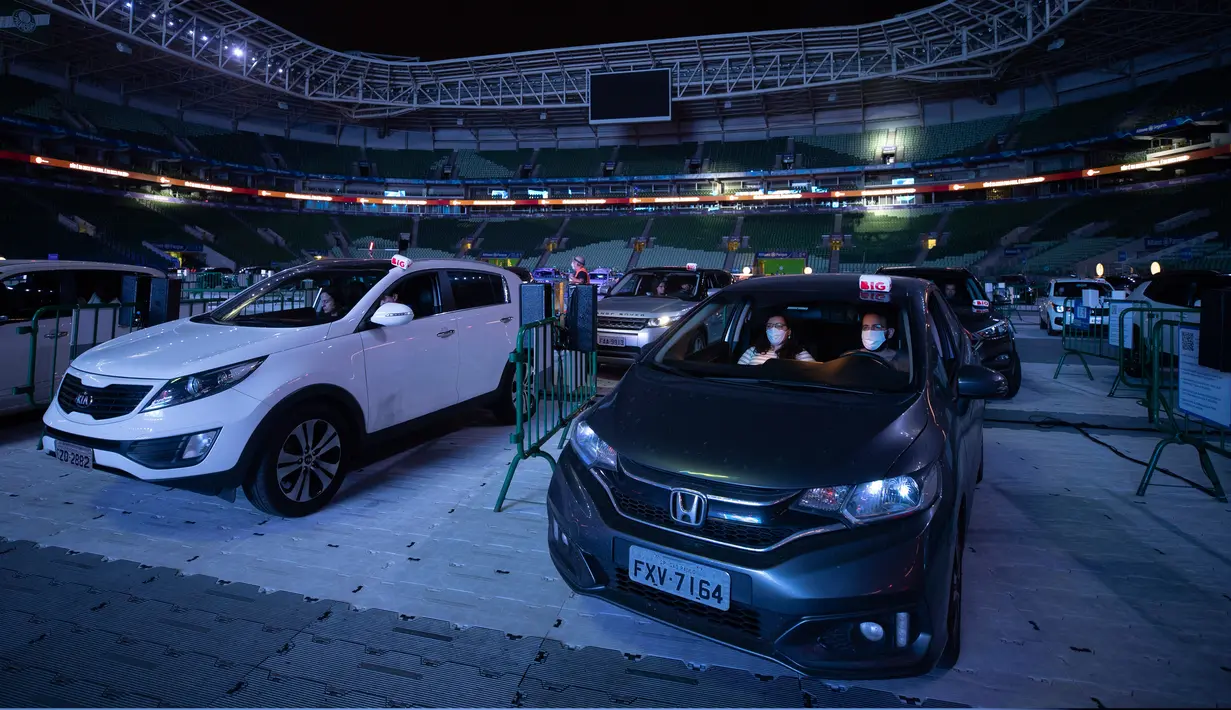 Orang-orang menonton film dari dalam mobil mereka di drive in yang dipasang di stadion sepak bola Palmeiras di Sao Paulo, Brasil, Kamis (25/6/2020). Stadion yang dapat menampung hingga 300 mobil tersebut berubah fungsi menjadi lokasi bioskop drive ini di masa pademi Covid-19. (AP Photo/Andre Penner)