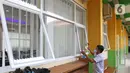 Petugas sedang membersihkan jendela di SMKN 51, Jakarta, Rabu (7/4/2021). SMKN 51 melakukan uji coba masuk sekolah dan Uji Sertifikasi Kompetensi (USK) dengan protokol kesehatan yang ketat. (Liputan6.com/Herman Zakharia)
