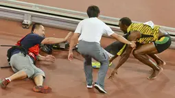 Pelari Jamaika, Usain Bolt langsung berdiri usai tertabrak kameramen yang mengendarai skuter saat dirinya melakukan selebrasi kemenangan meraih medali emas di nomor 200 meter di Kejuaran Dunia Atletik di Beijing, Kamis (27/8). (REUTERS/Stringer CHINA OUT)