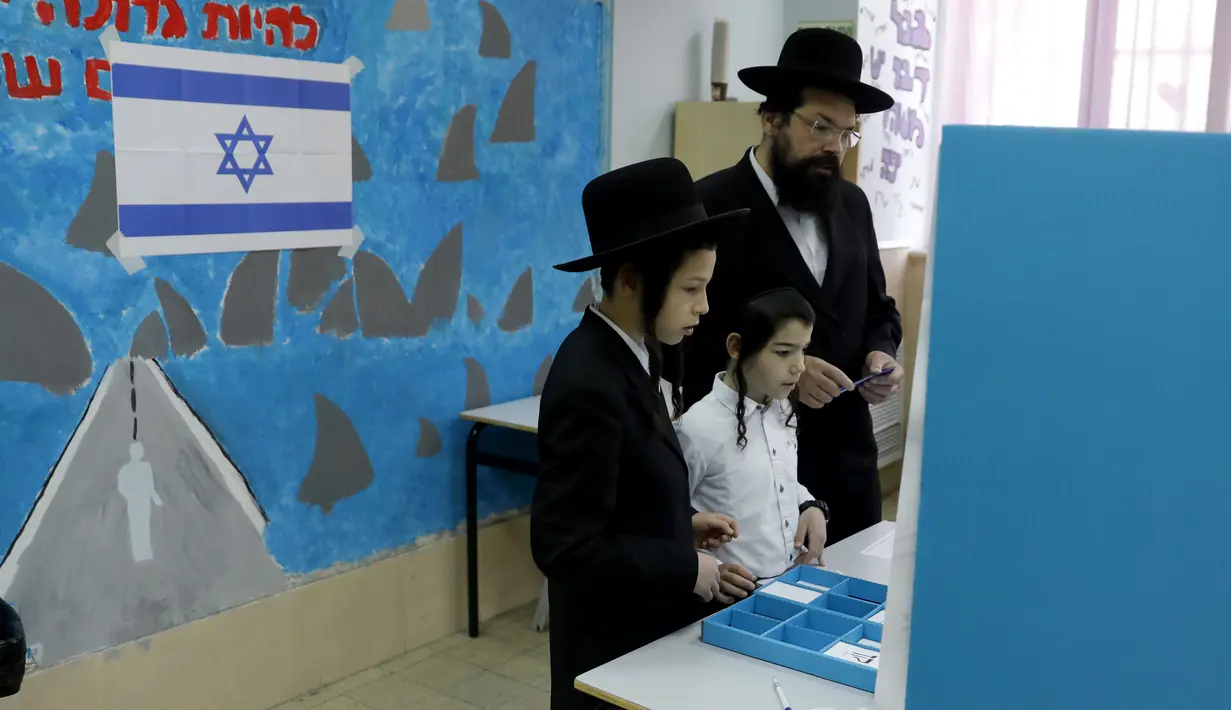 Anak-anak menyaksikan pria Yahudi ultra-Ortodoks memberikan suaranya selama pemilihan parlemen Israel di Yerusalem (9/4). Warga Israel hari ini memberikan suara dalam pemilihan tingkat tinggi yang akan memutuskan masa jabatan PM Benjamin Netanyahu. (AFP Photo/Menahem Kahana)