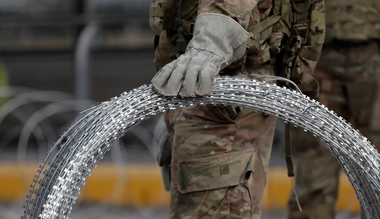 Tentara membawa kawat duri untuk dipasang di perbatasan AS-Meksiko di Jembatan Internasional McAllen-Hidalgo, Texas, Jumat (2/11). Selain Trump, Barack Obama dan George W Bush juga pernah mengerahkan pasukan ke perbatasan AS-Meksiko. (AP Photo/Eric Gay)