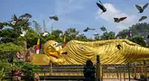 Sejumlah burung merpati terbang di samping patung Buddha raksasa di Maha Vihara Mojopahit, Mojokerto, Jawa Timur, pada tanggal 15 Mei 2024. (JUNI KRISWANTO/AFP)