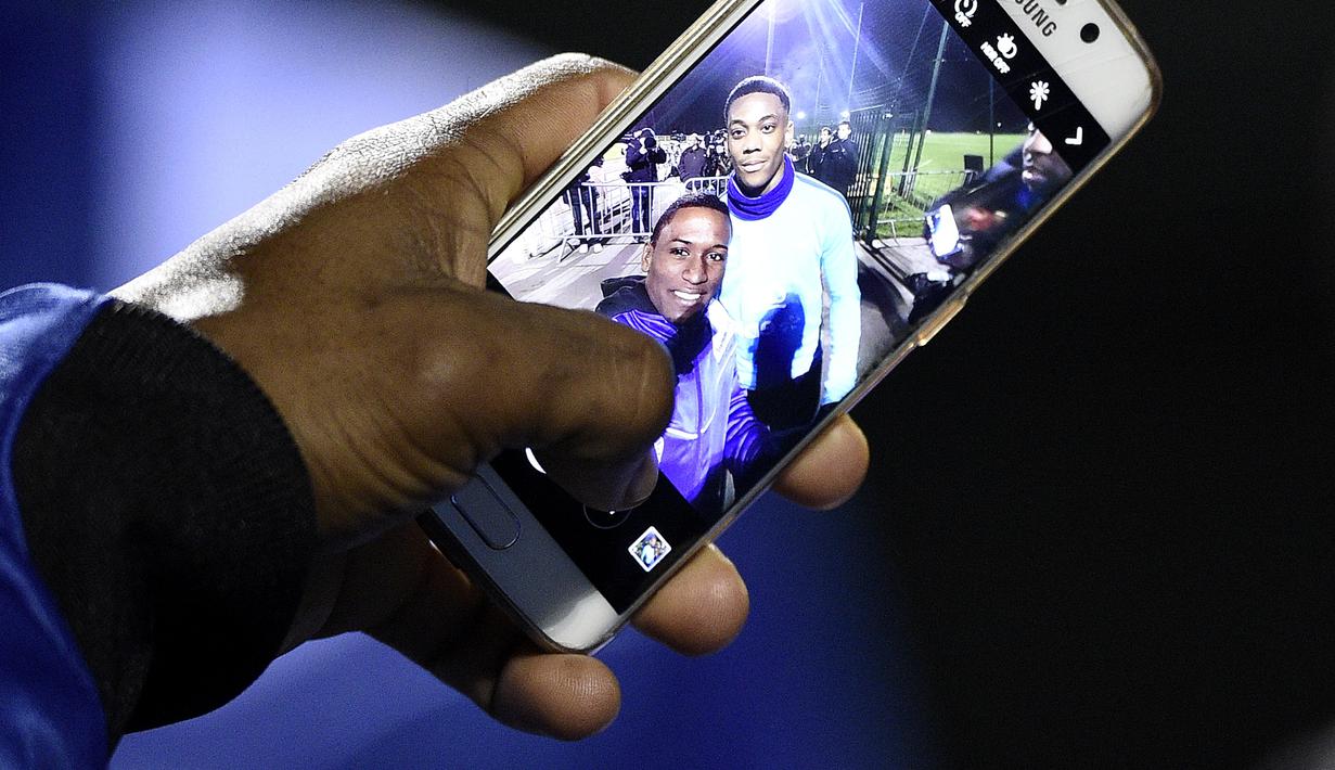 Pemain Manchester United  Anthony Martial (kanan) berfoto selfie bersama fans saat sesi latihan sebelum laga persahabatan Perancis vs Jerman di Clairefontaine-en-Yvelines, Selasa (10/11/2015) WIB. (AFP Photo/Franck Fife)