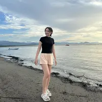 Bermain di pantai, Happy Asmara tampil dengan atasan kaos hitam ketat dipadukan celana pendek warna peach dan sandal karet putihnya.  (@happy_asmara77)