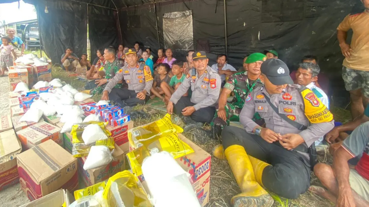 Warga korban banjir bersama kepolisian dan TNI di tenda pengungsian.