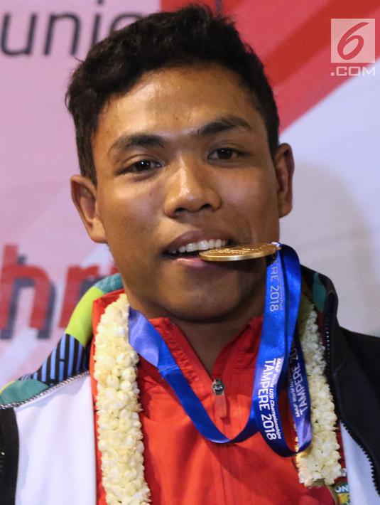 Pelari muda Indonesia, Lalu Muhammad Zohri menggigit medali emas saat upacara penyambutan di Terminal 3 Bandara Soetta, Tangerang, Selasa (17/7). Lalu M Zohri meraih emas lari 100m putra di Kejuaraan Dunia Atletik U-20. (Liputan6.com/Helmi Fithriansyah)
