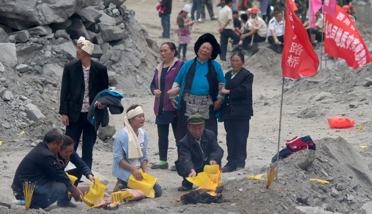 Keluarga serta kerabat korban membakar dupa dan kertas ritual untuk menenangkan arwah orang yang tewas di lokasi tanah longsor di desa Xinmo, Sichuan, China (25/6). Akibat longsor diperkirakan 118 orang masih hilang. (AP Photo / Ng Han Guan)