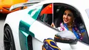 Seorang kontestan Miss World tersenyum sambil membawa bendera China saat mengikuti pawai menggunakan supercar di Sanya, Provinsi Hainan, China, (7/11). Pawai ini membuka kontes kecantikan Miss World ke-67. (AFP Photo/Str/China Out)