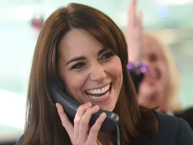 Duchess of Cambridge, Kate Middleton tertawa sambil menggenggam gagang telepon saat menjadi broker dalam acara amal tahunan ICAP di London, Inggris, Rabu (9/12/2015). (AFP PHOTO/POOL/JEREMY Selwyn)