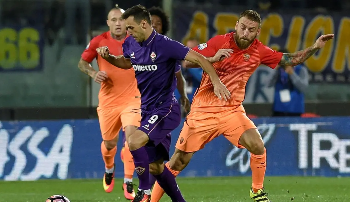 Pemain AS Roma, Daniele De Rossi (kanan), berebut bola dengan pemain Fiorentina, Nikola Kalinic, pada lanjutan Serie A di Artemio Franchi, Firenze, Senin (19/9/2016) dini hari WIB. (AFP/Andreas Solaro)