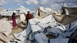 Para pengungsi di Gaza hanya punya dua pilihan tempat berlindung. Tampak dalam foto, seorang perempuan Palestina pengungsi merapikan terpal tenda keluarga saat wilayah tersebut dilanda hujan dan kondisi musim dingin yang dingin, di Kota Gaza pada 28 Desember 2025. (Omar AL-QATTAA/AFP)