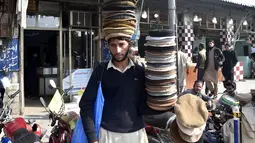 Seorang penjual menjajakan topi tradisional di sebuah jalan di Peshawar, Pakistan barat laut, pada 28 Desember 2020. Topi tradisional yang terbuat dari bahan wol ini sangat populer di kalangan warga Pakistan selama musim dingin. (Xinhua/Saeed Ahmad)