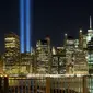 Sepasang kekasih menikmati ‘Tribute in Light’ dari sisi Brooklyn Promenade untuk mengenang tragedi serangan WTC di New York, Minggu (10/9). Kota New York memperingati 16 tahun tragedi serangan bom pada 11 September 2001 silam. (AP Photo/Mark Lennihan)