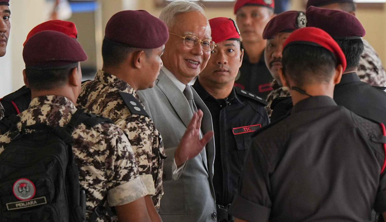 Mantan Perdana Menteri Malaysia, Najib Razak (tengah) dikawal oleh petugas penjara saat tiba di Kompleks Pengadilan Tinggi Kuala Lumpur, Malaysia, Senin 22 Desember 2025. Mahkamah Tinggi Kuala Lumpur pada Senin 22 Desember 2025 menolak permohonan mantan Perdana Menteri Malaysia, Najib Razak, untuk menjalani sisa masa hukumannya sebagai tahanan rumah. (AP Photo/Azneal Ishak)
