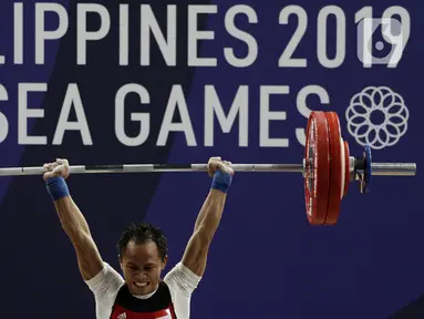 Lifter putra Indonesia, Suratman melakukan angkatan saat SEA Games 2019 cabang angkat besi nomor 55 kg di Stadion Rizal Memorial, Manila, Minggu (1/12/2019). Dirinya meraih perak dengan total angkatan 250 kg. (Bola.com/M Iqbal Ichsan)