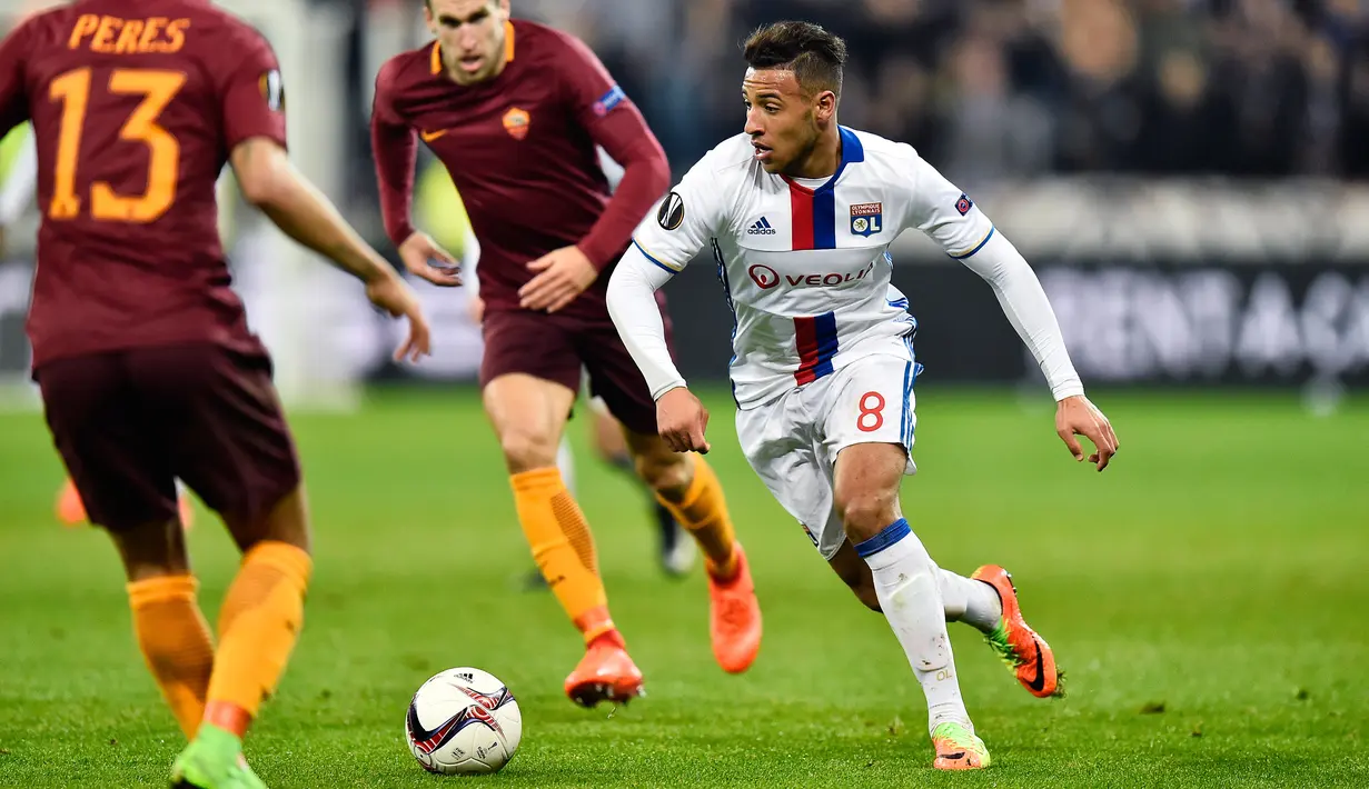 Gelandang Lyon, Corentin Tolisso (kanan) berusaha membawa bola melewati pemain AS Roma pada leg pertama babak 16 besar Liga Europa di Stade de Lyon, Prancis, (9/3). Lyon berhasil mengalahkan AS Roma dengan skor 4-2. (AFP Photo / Romain Lafabregue)