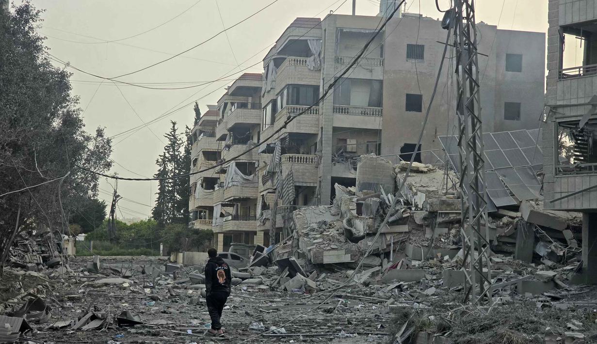 Serangan Israel ke Lebanon juga berdampak besar pada kelangsungan hidup warga sipil dan memicu pengungsian besar-besaran. Tampak dalam foto, seorang pria berjalan melewati puing-puing bangunan yang hancur di lokasi serangan udara Israel di daerah Al Hosh dekat kota pesisir Tyre, Lebanon, pada Sabtu 4 April 2026. (Kawnat HAJU/AFP)