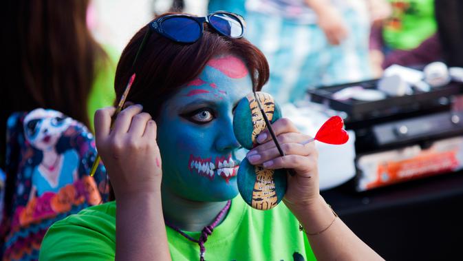 Seorang wanita merias wajahnya sebelum Zombie Walk di Mexico City, Minggu (11/11). Ratusan orang dengan penampilan seram dan mengenakan pakaian compang-camping berkumpul di pusat bersejarah ibu kota Meksiko dalam acara tahunan tersebut. (AP/Claudio Cruz)