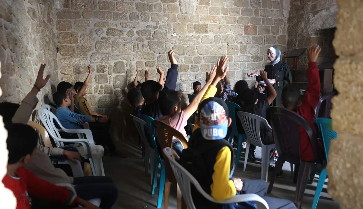 Anak-anak Palestina menghadiri kelas di sekolah bersejarah "Al-Kamaliya al-Othmanya" di Kota Tua Gaza yang menjadi bagian dari inisiatif sukarelawan yang diorganisir oleh para guru pengungsi, di Kota Gaza pada 2 November 2025. Pembukaan kembali sekolah-sekolah di Gaza memungkinkan anak-anak melanjutkan pendidikan formal setelah terhenti selama sekitar dua tahun akibat konflik. (Omar AL-QATTAA/AFP)